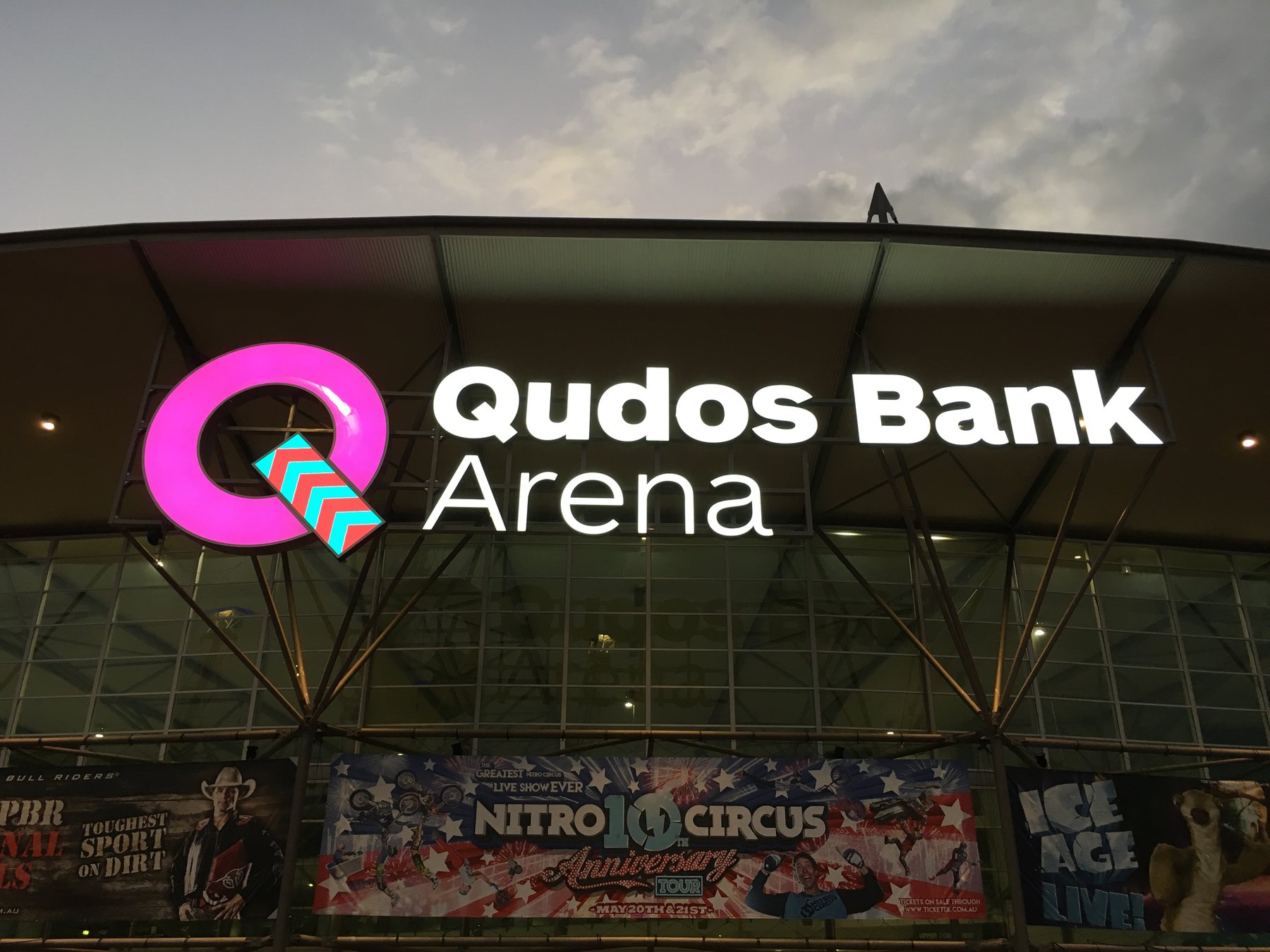 Qudos Bank Arena illuminated logo, pink, at dusk